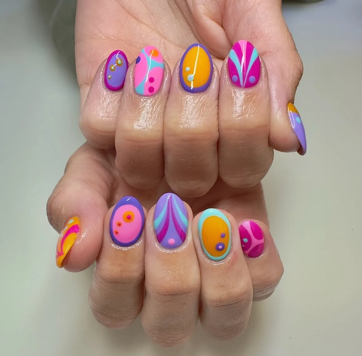 Color-blocked abstract nails in purple, pink, teal, and orange