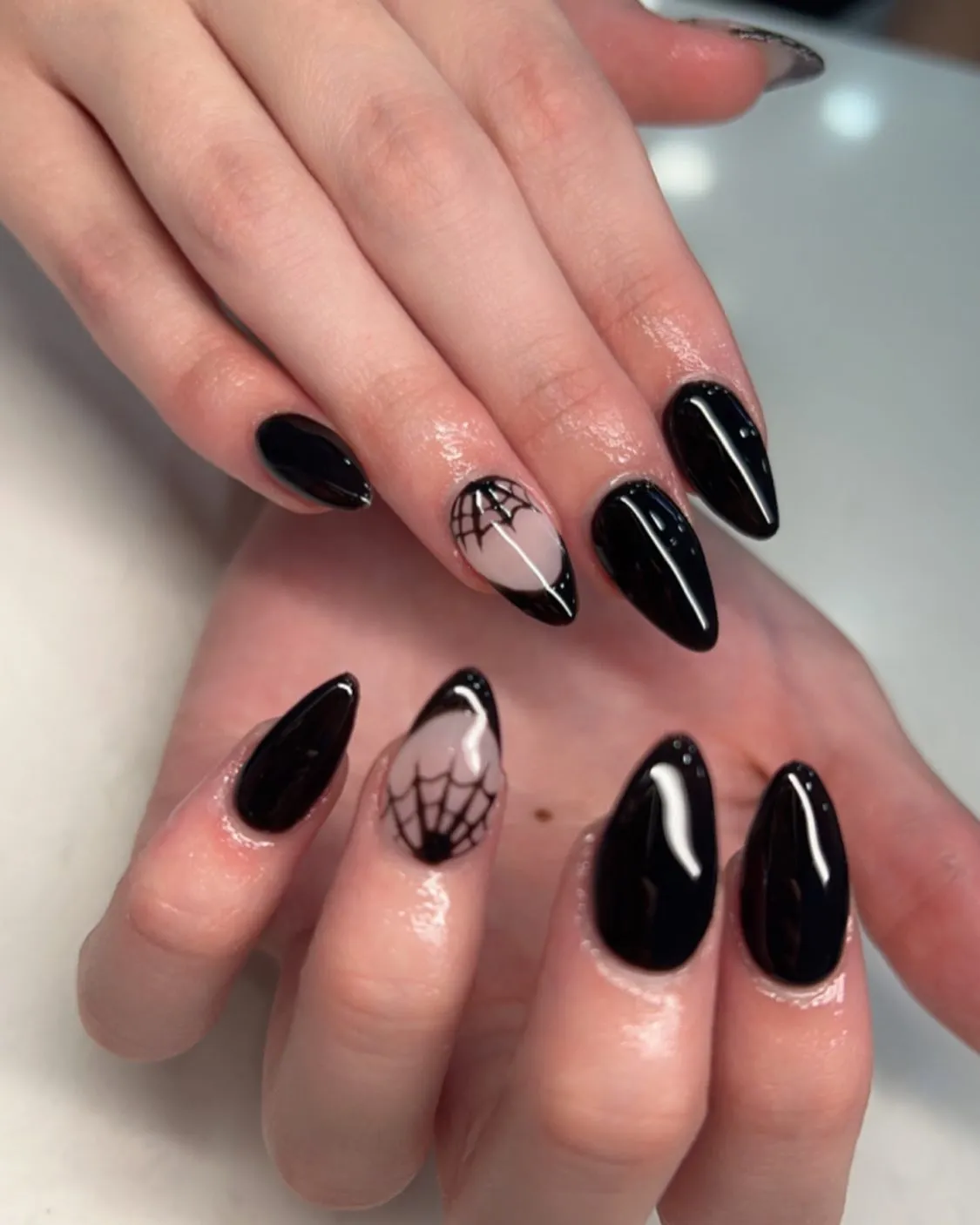 Glossy black nails with nude spiderweb accent nails