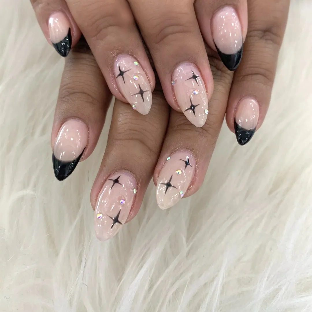 Black French tips with starburst motifs and iridescent gems
