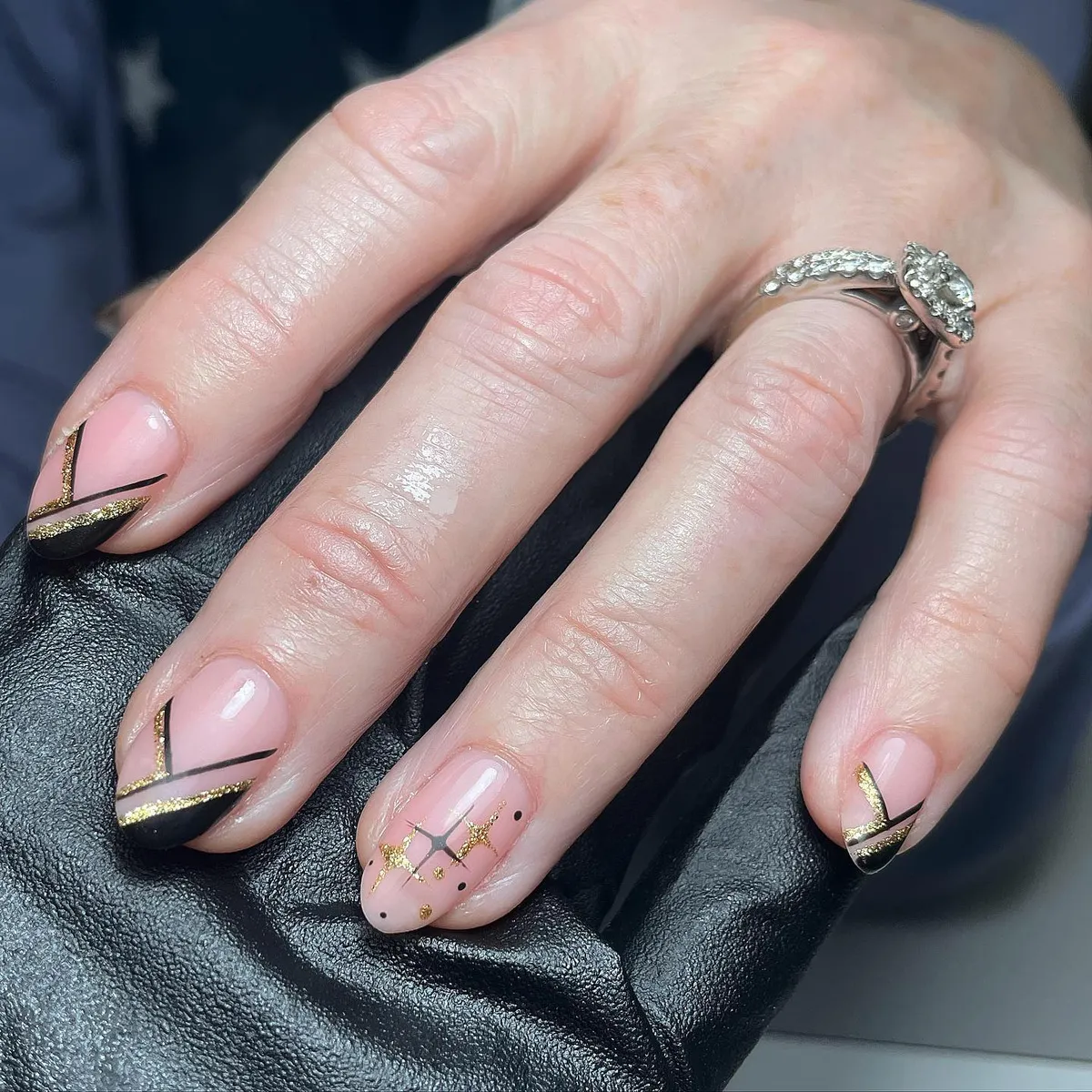 Short nude nails with black diagonal tips and gold striping