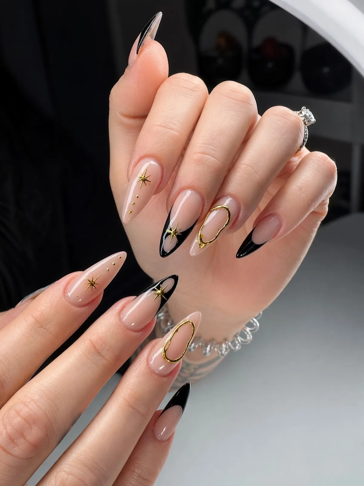 Glossy nude with black tips and gold starburst accents