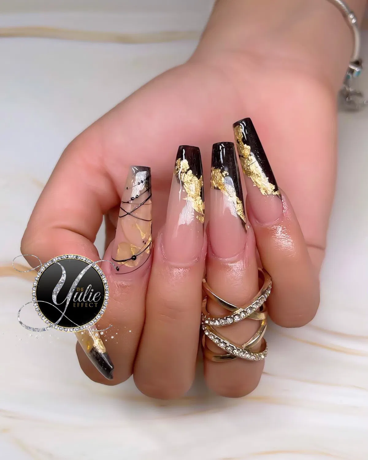 Extra-long nude nails with black tips and gold foil accents