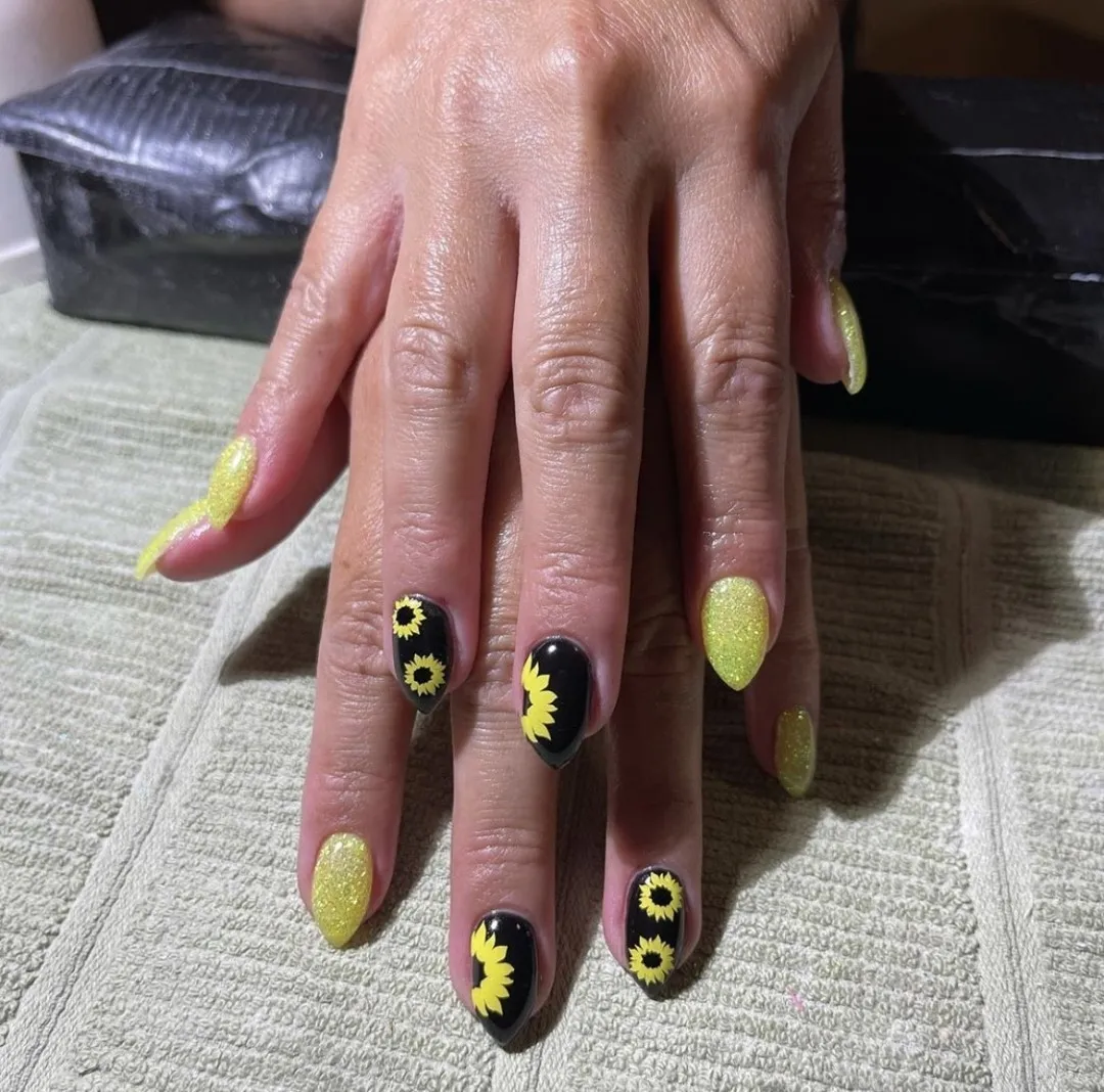 Yellow glitter and black sunflower accents on almond nails