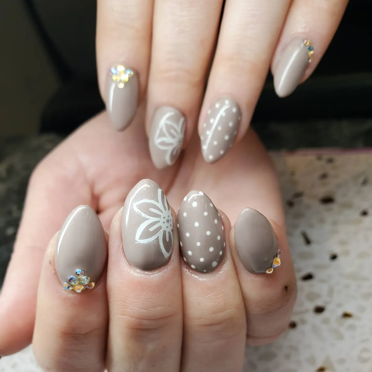 Taupe nails with white line art, dots, and rhinestones