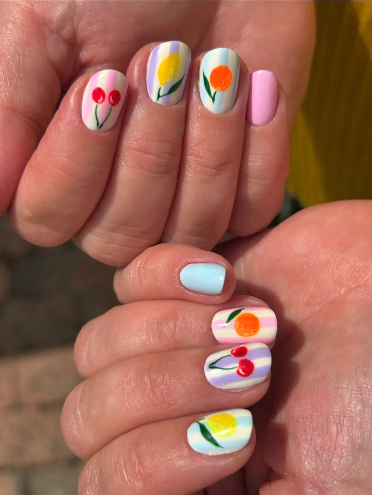 Pastel striped nails with simple fruit motifs