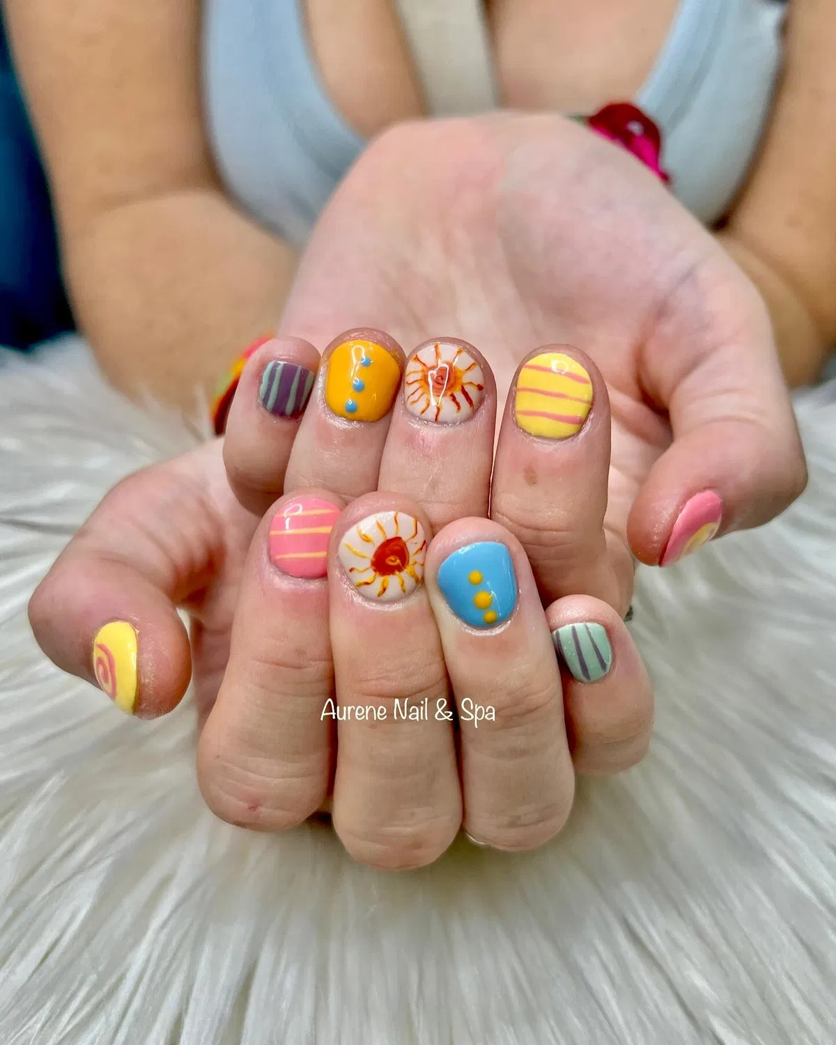 Mini sun-and-stripe nail art in bright pastels