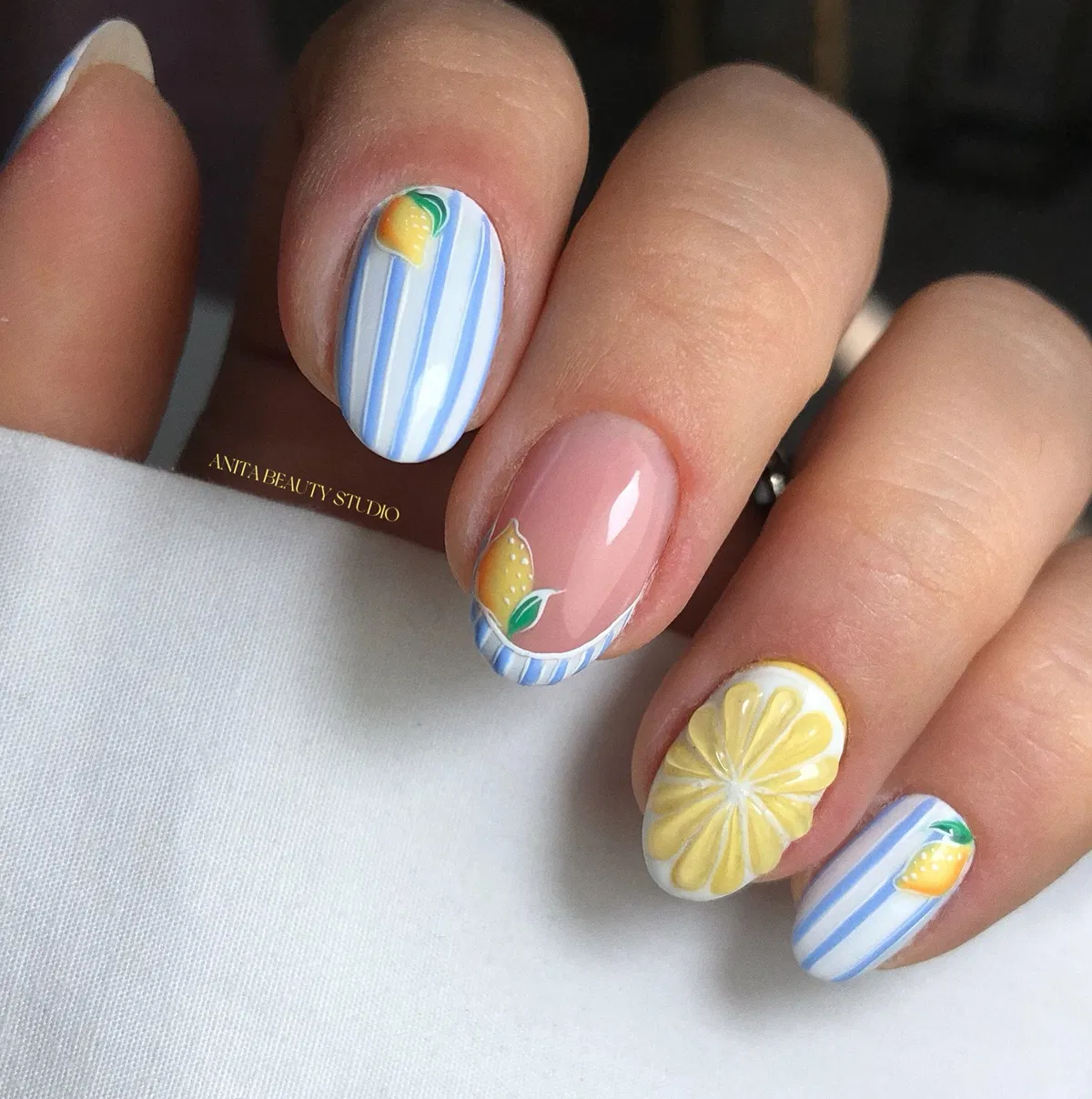 Short rounded nails with striped tips and lemon slice accent