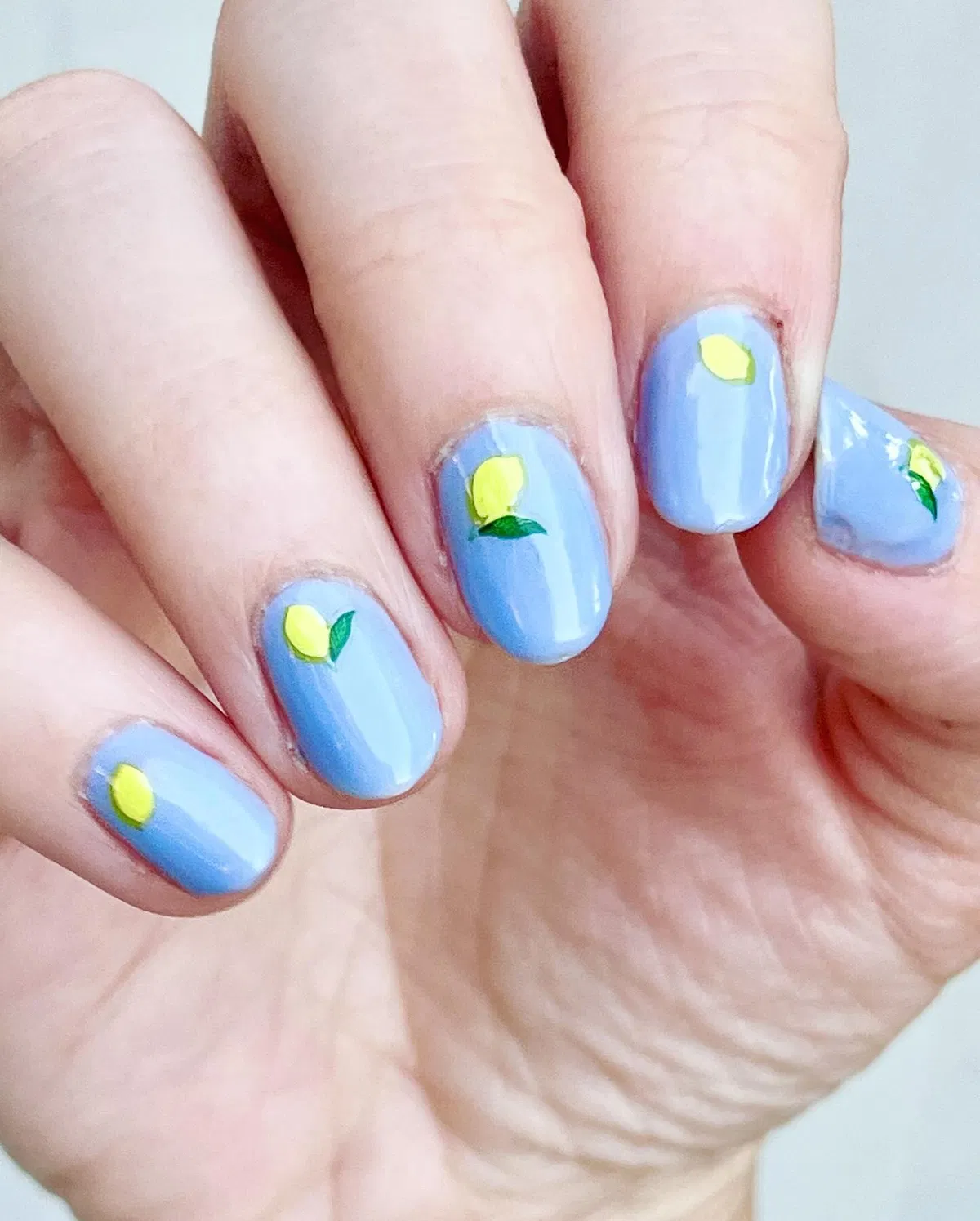 Simple light blue nails with tiny yellow lemon motifs