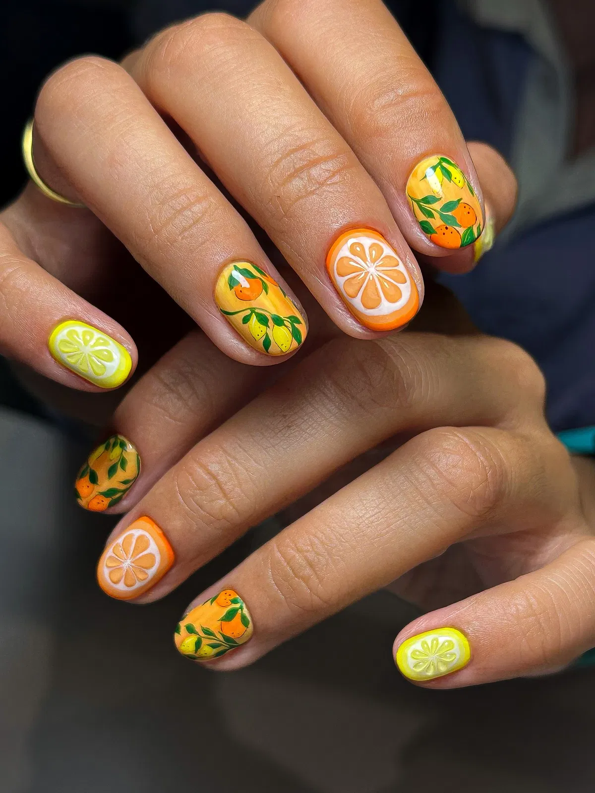 Mixed citrus slices and leafy fruit on short glossy nails