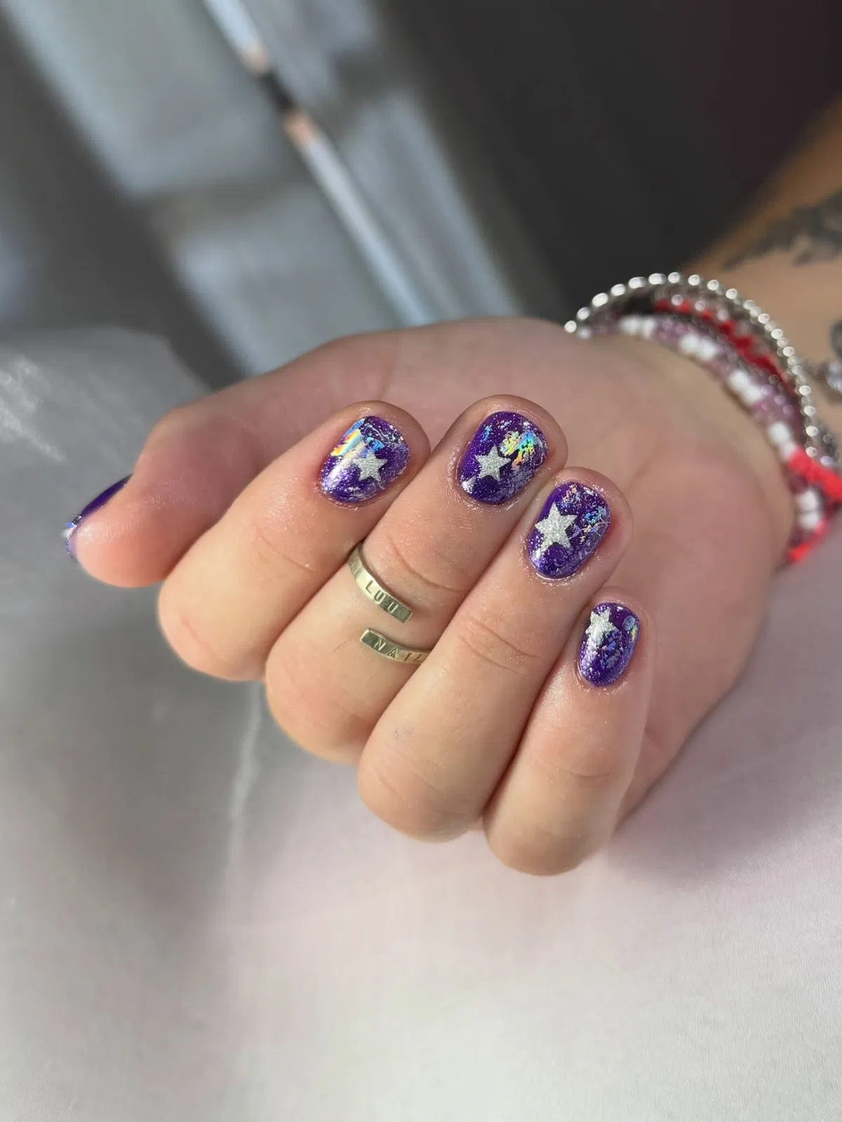 Purple glitter-speckled nails with silver star shapes