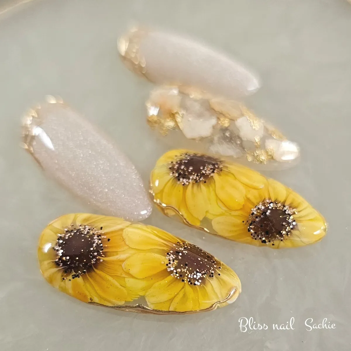 Sunflower nail tip set with gold-outlined edges and glitter accents
