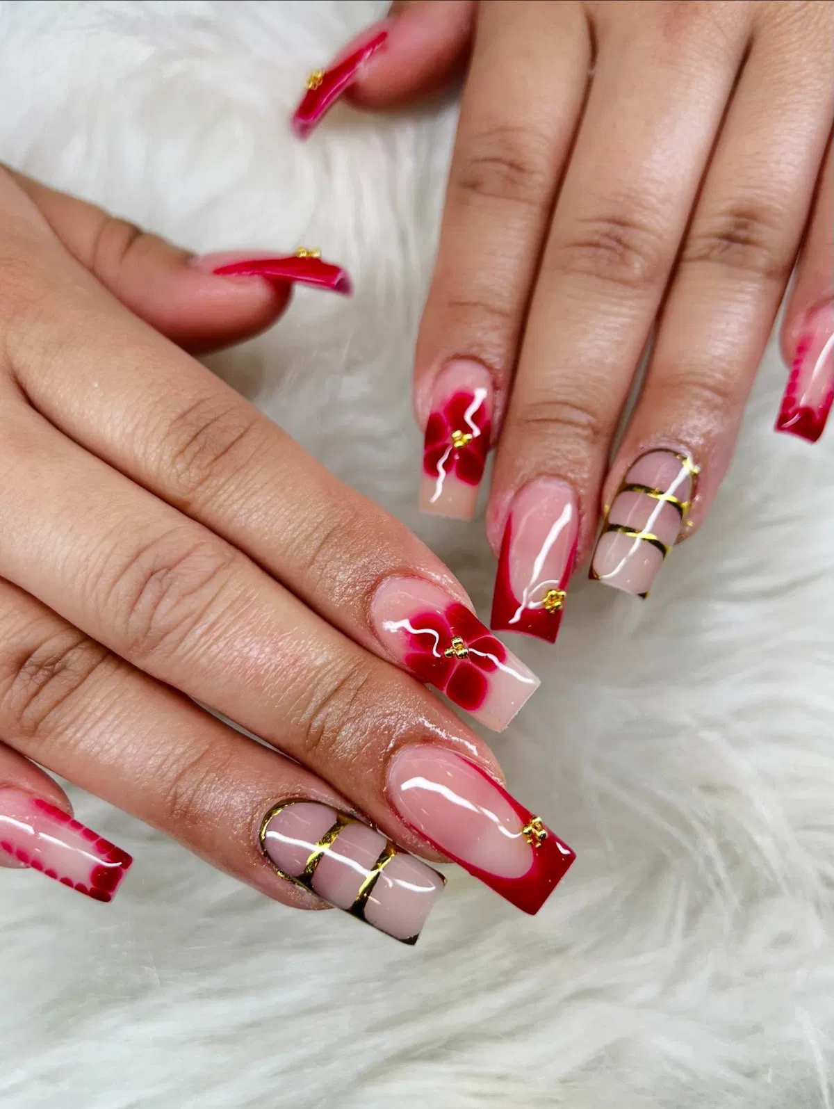 Red French tips with gold striping and floral accents