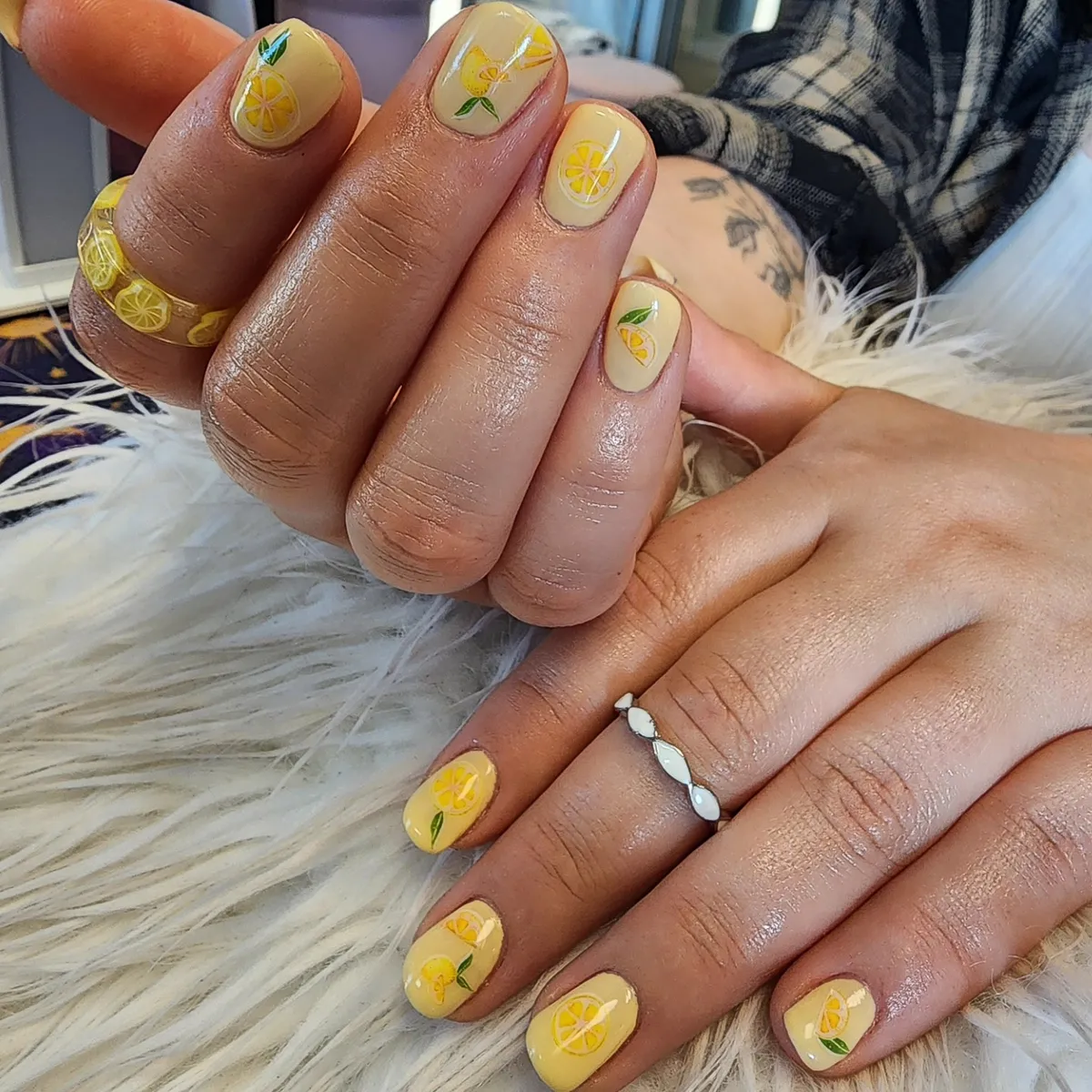 Glossy pale yellow nails with lemon-and-leaf mini art