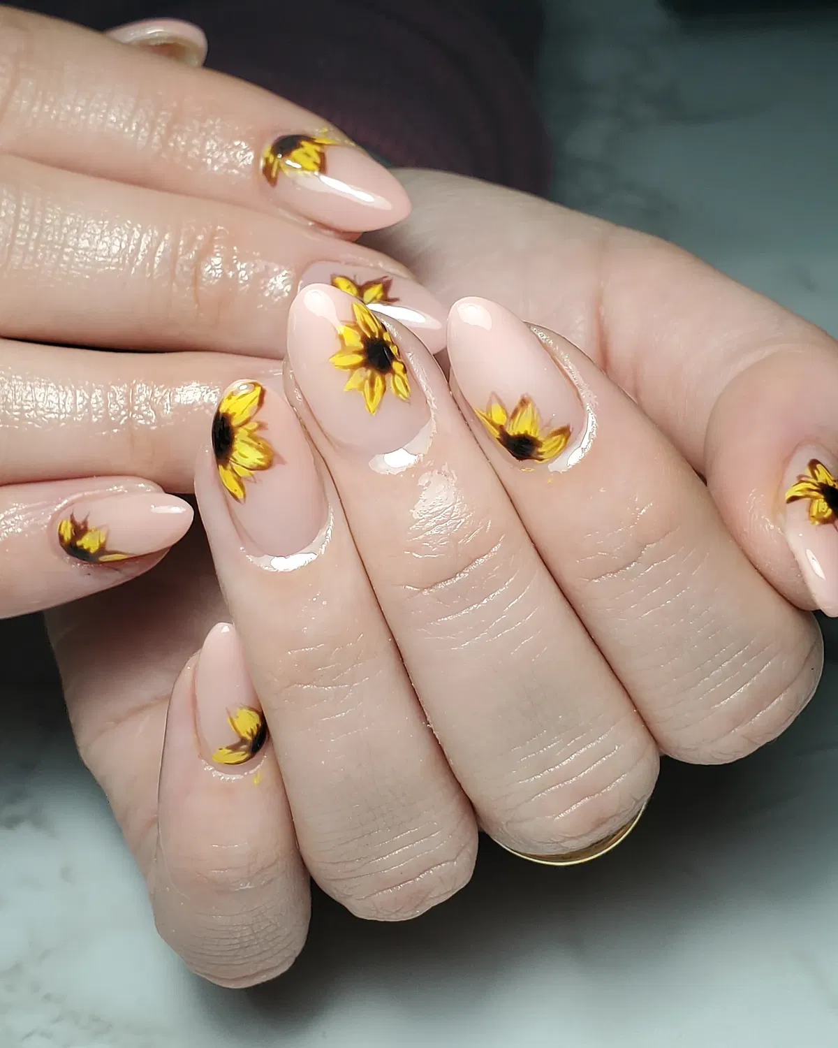 Nude almond nails with scattered sunflower motifs