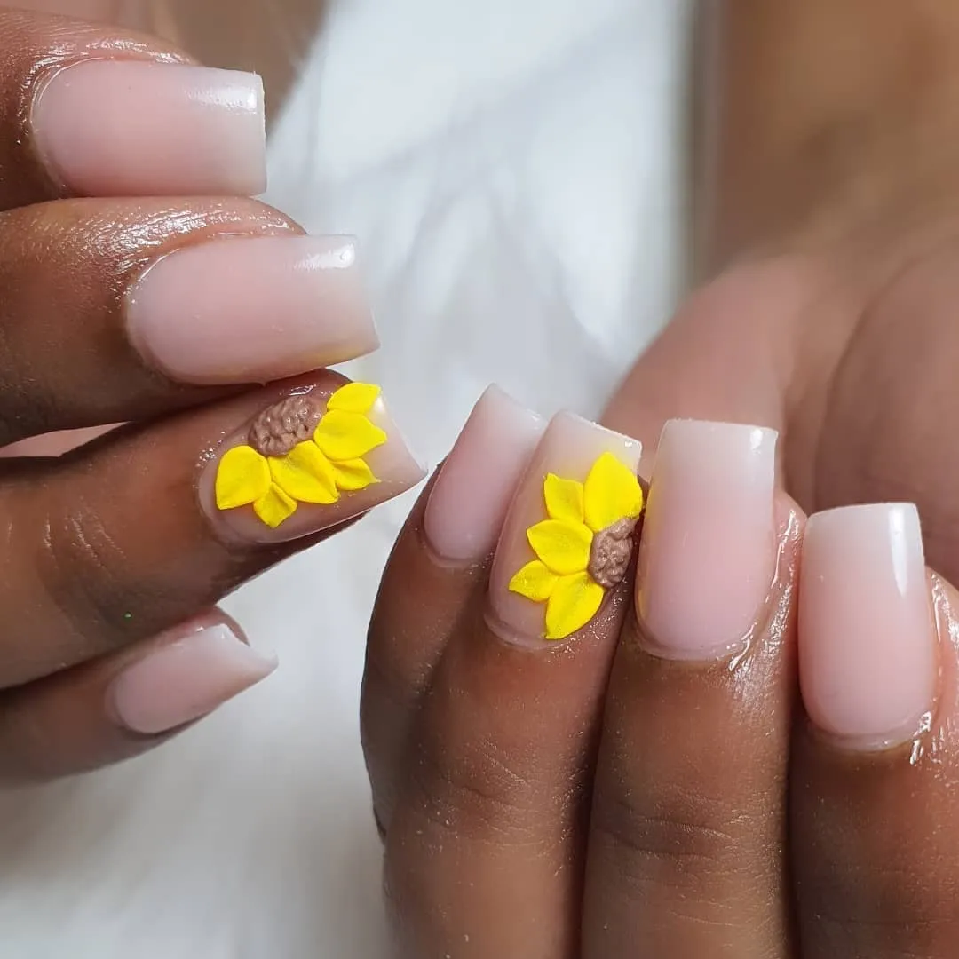 Milky nude-pink square nails with textured sunflower accents