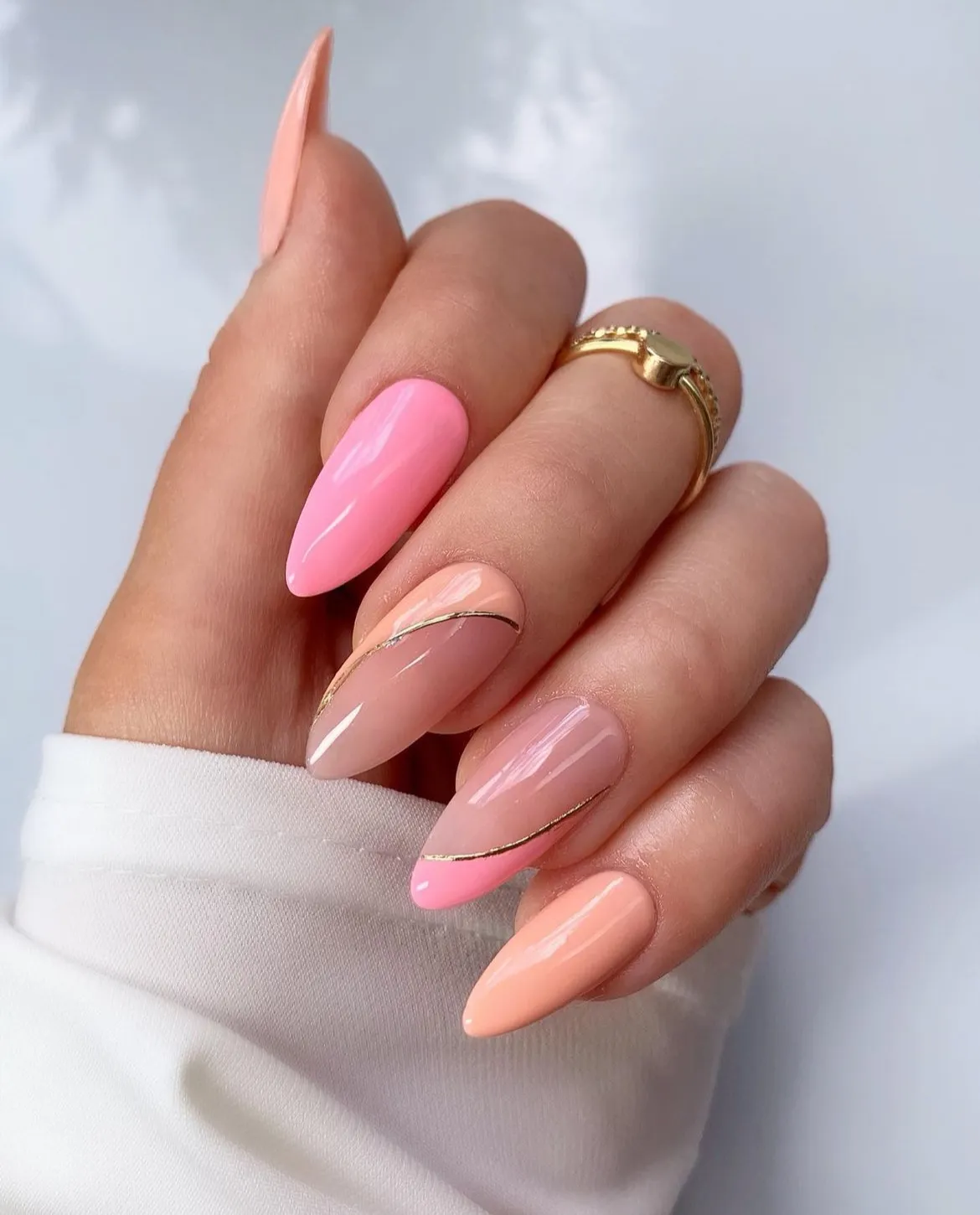 Pink and peach glossy nails with thin gold curves