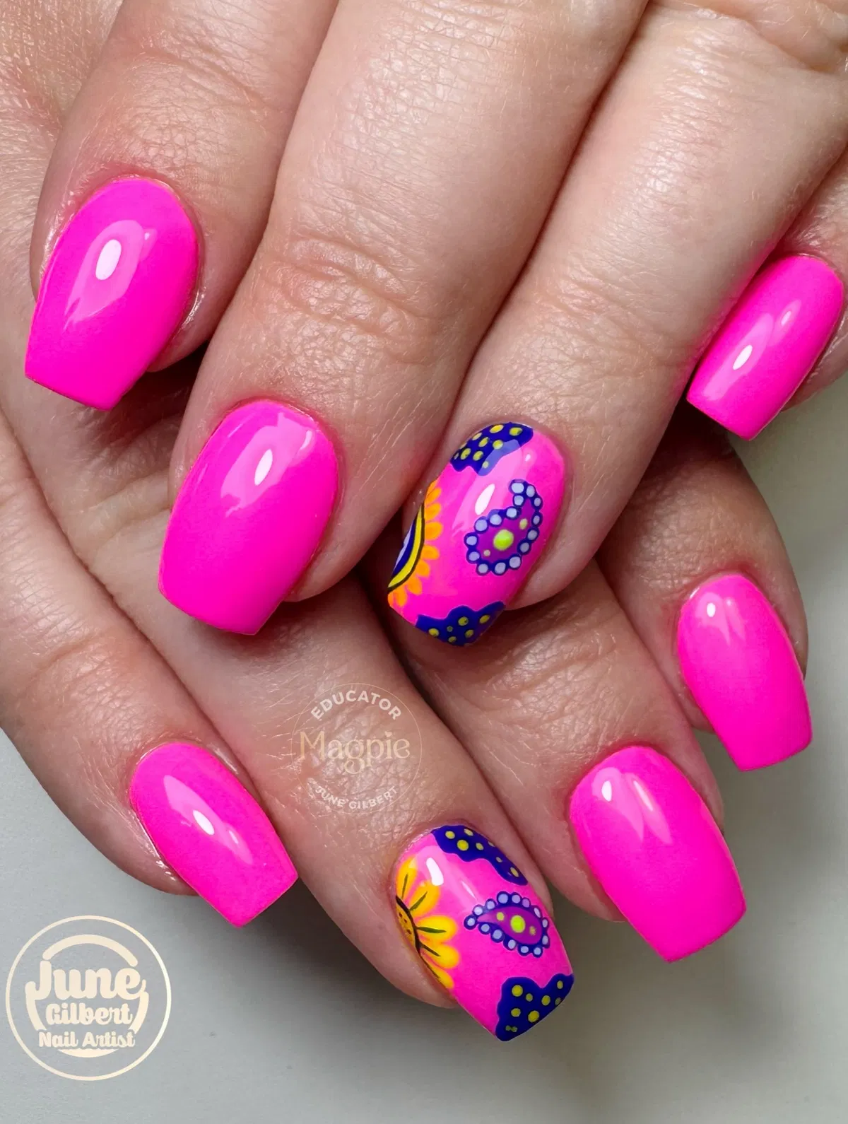 Neon hot pink nails with bold blue-and-yellow accent art
