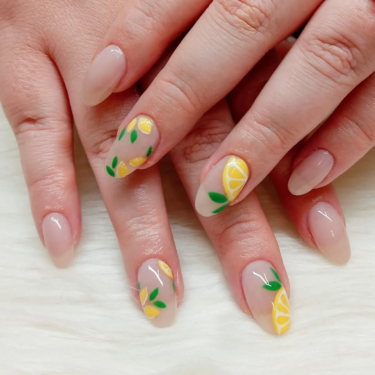 Neutral almond nails with lemon slices and green leaves