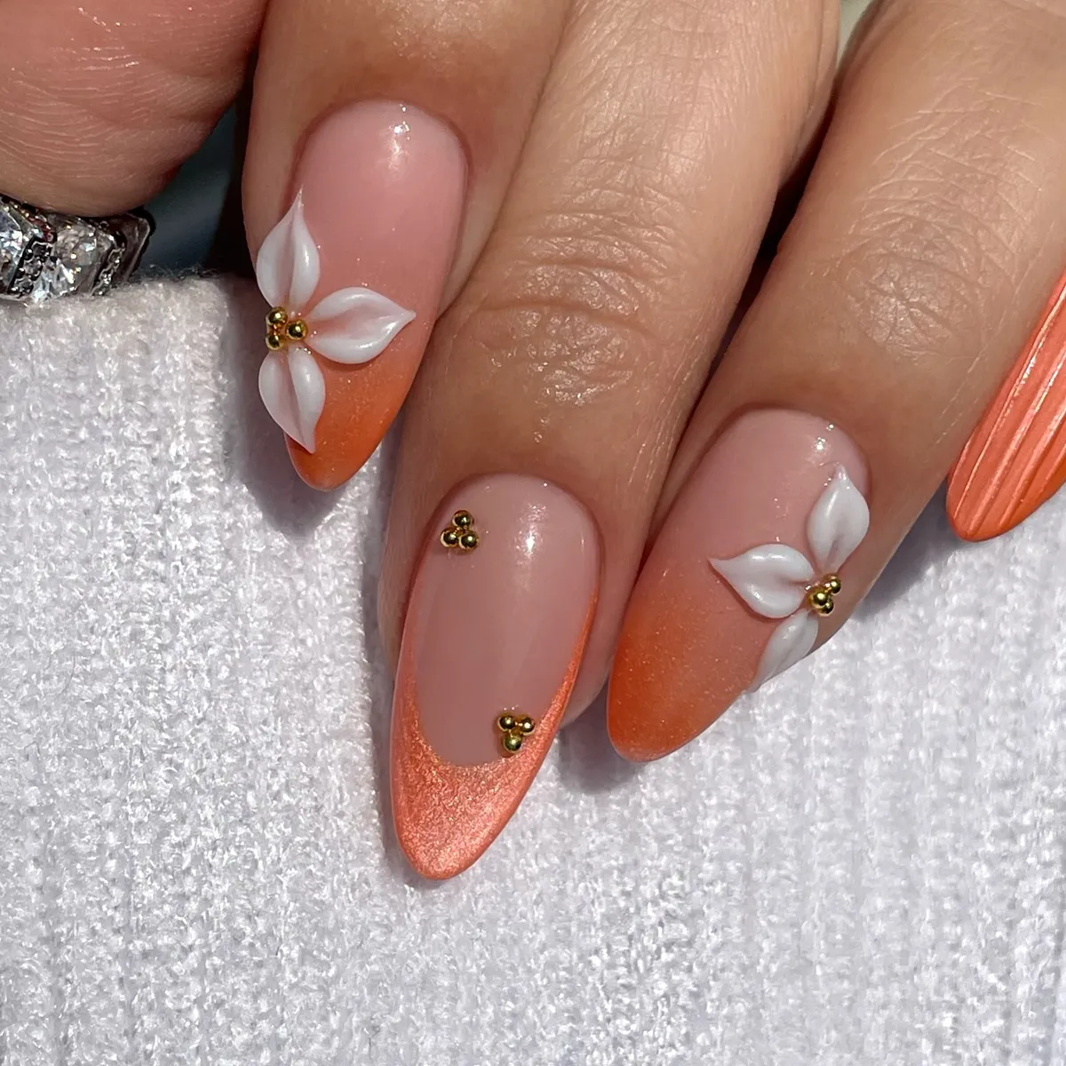 Nude base with metallic orange tips and 3D white flowers