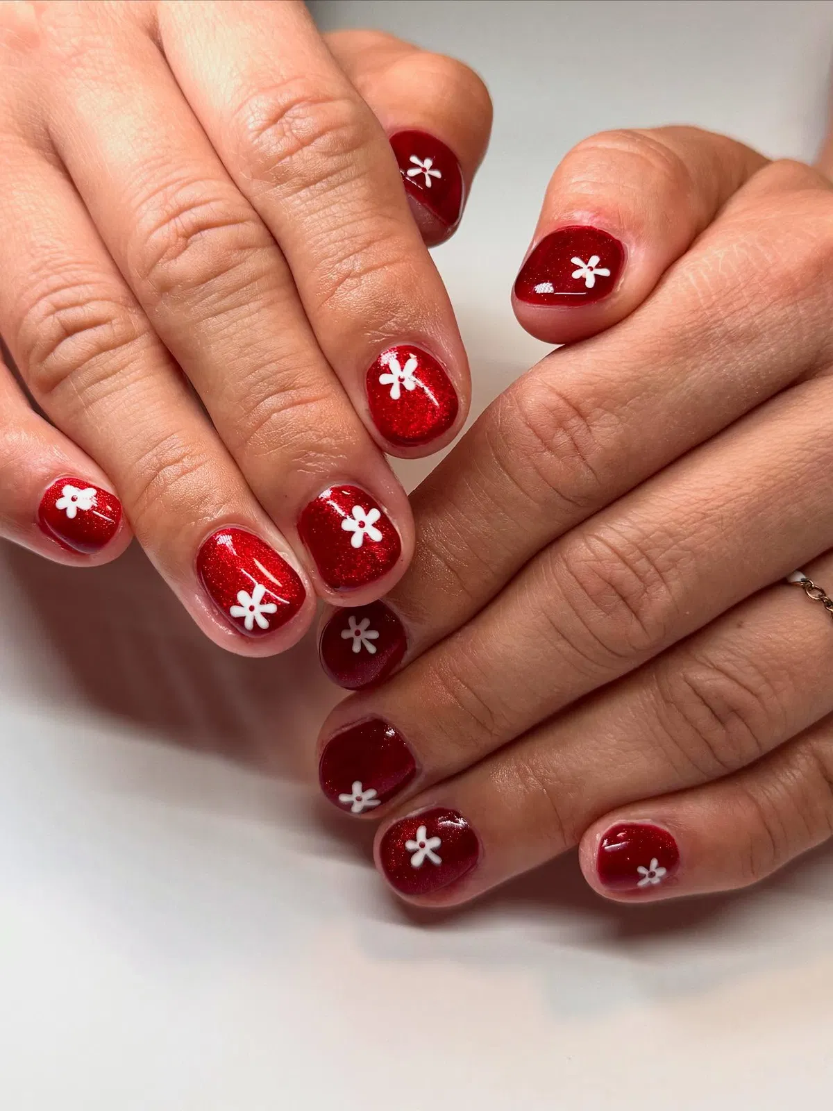 Deep red sparkle nails with small white flowers