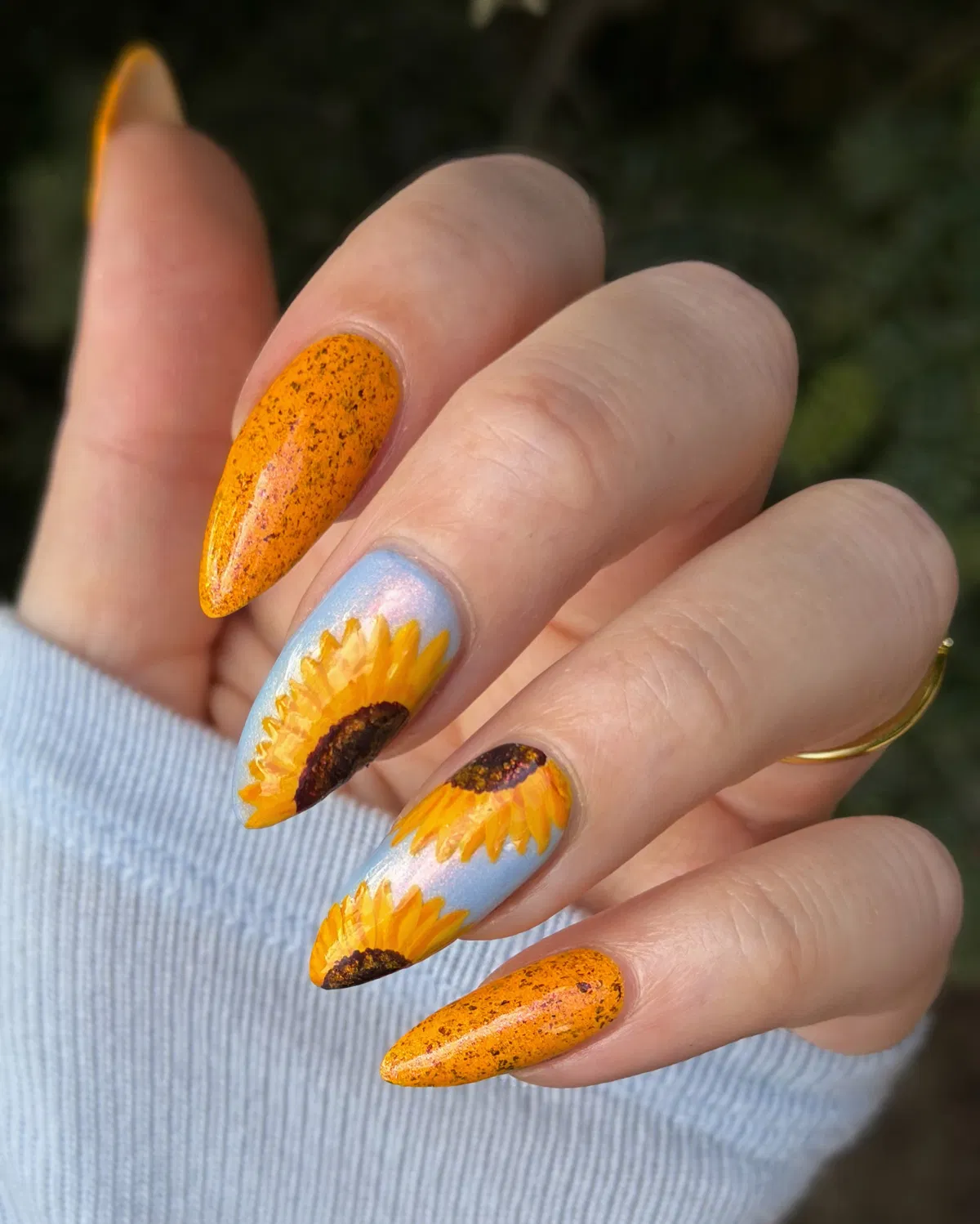 Orange speckle nails with large sunflowers on light blue