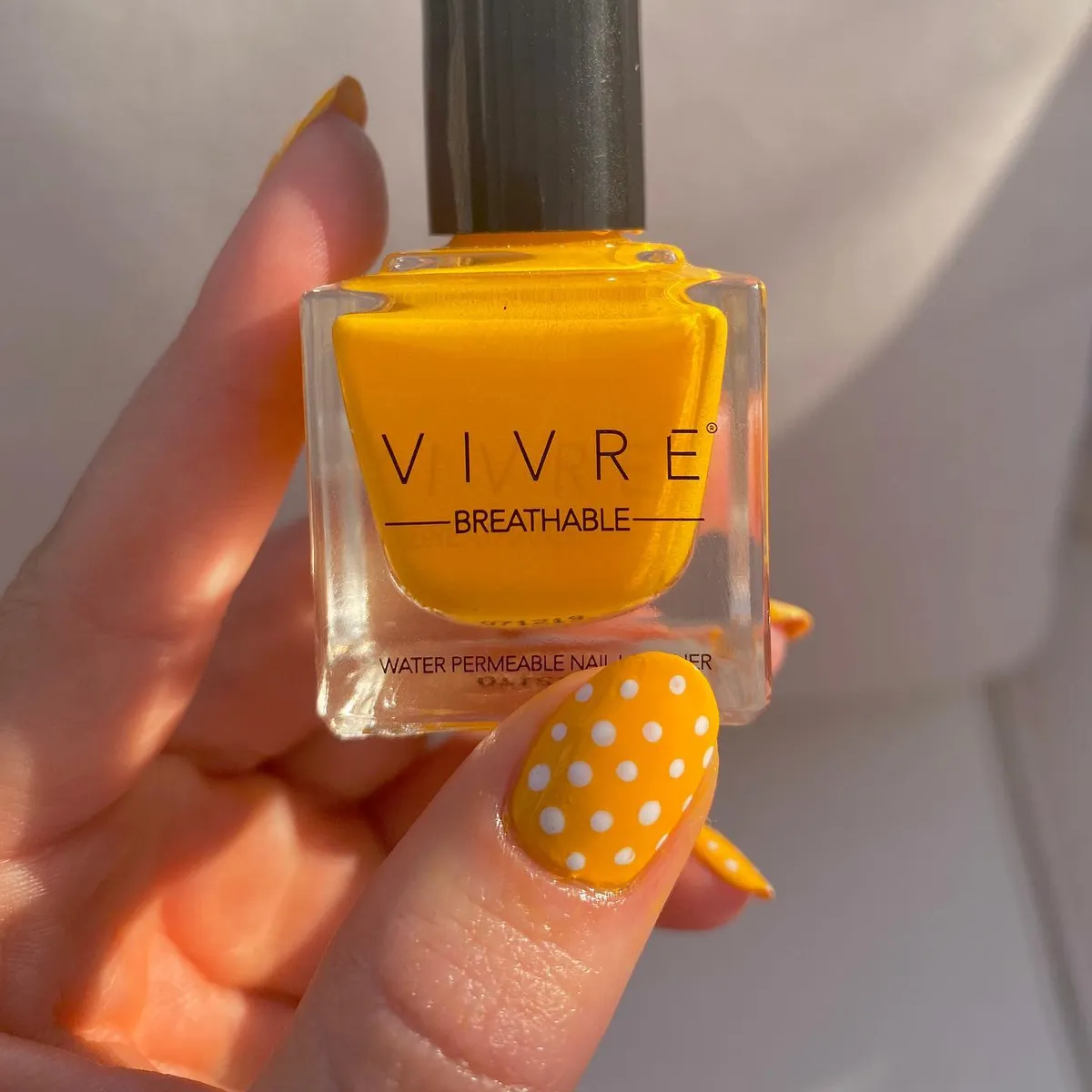 Yellow polka-dot nail with visible lacquer bottle