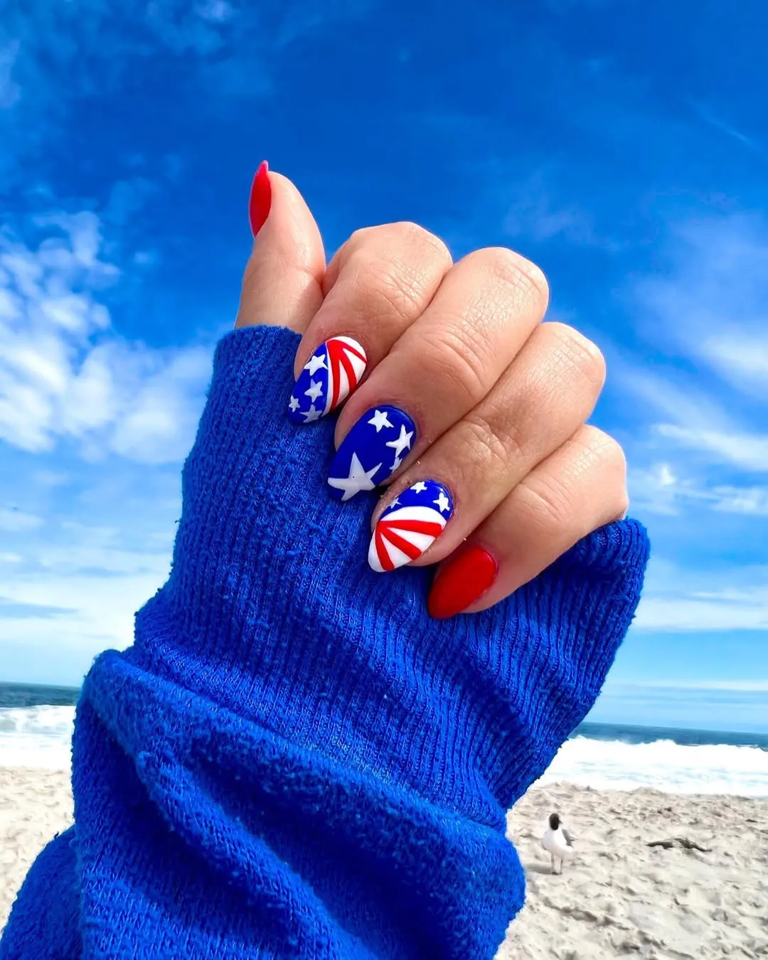 Beach photo with starry blue nails and curved stripe accents