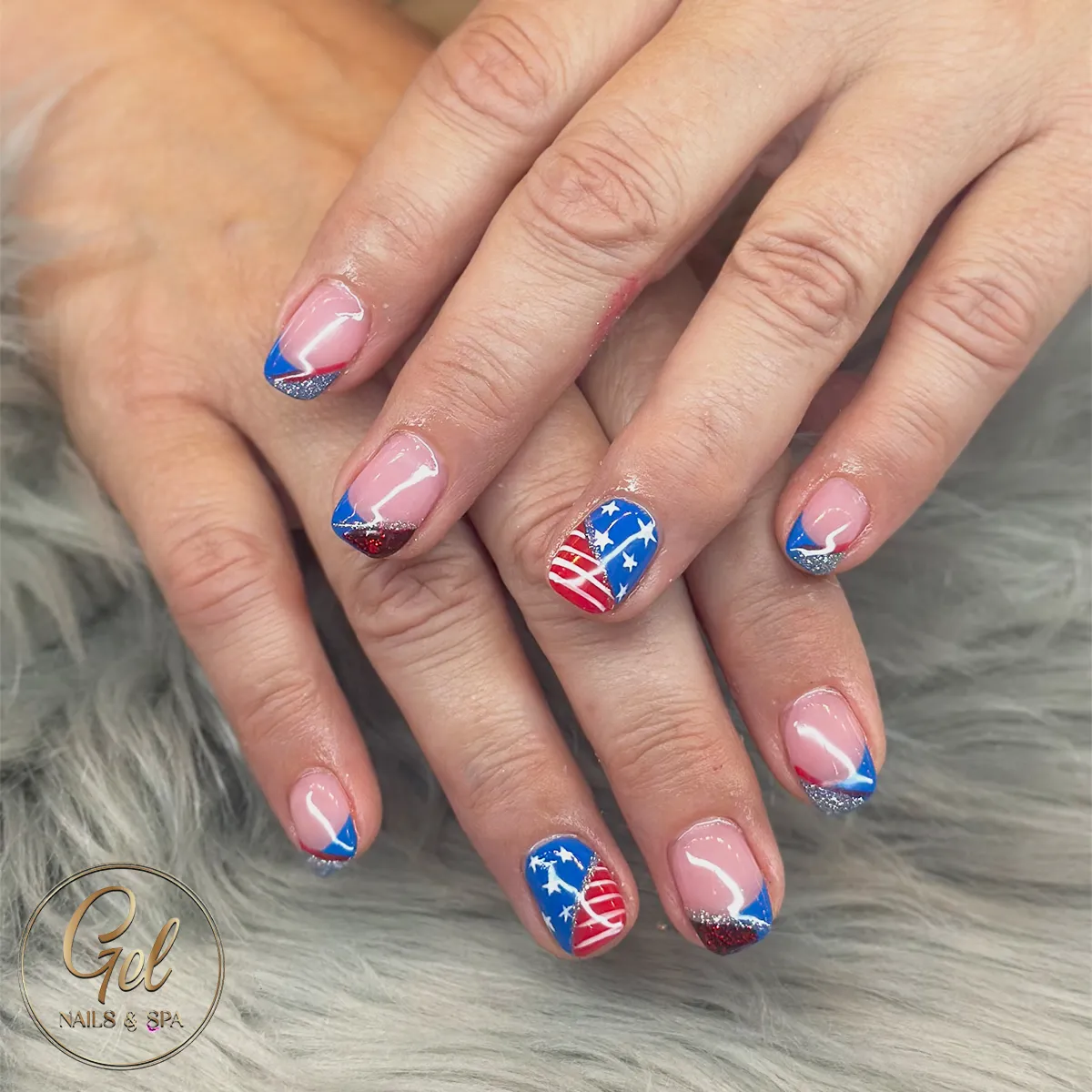 Diagonal French tips with glitter edges and star-and-stripe accents