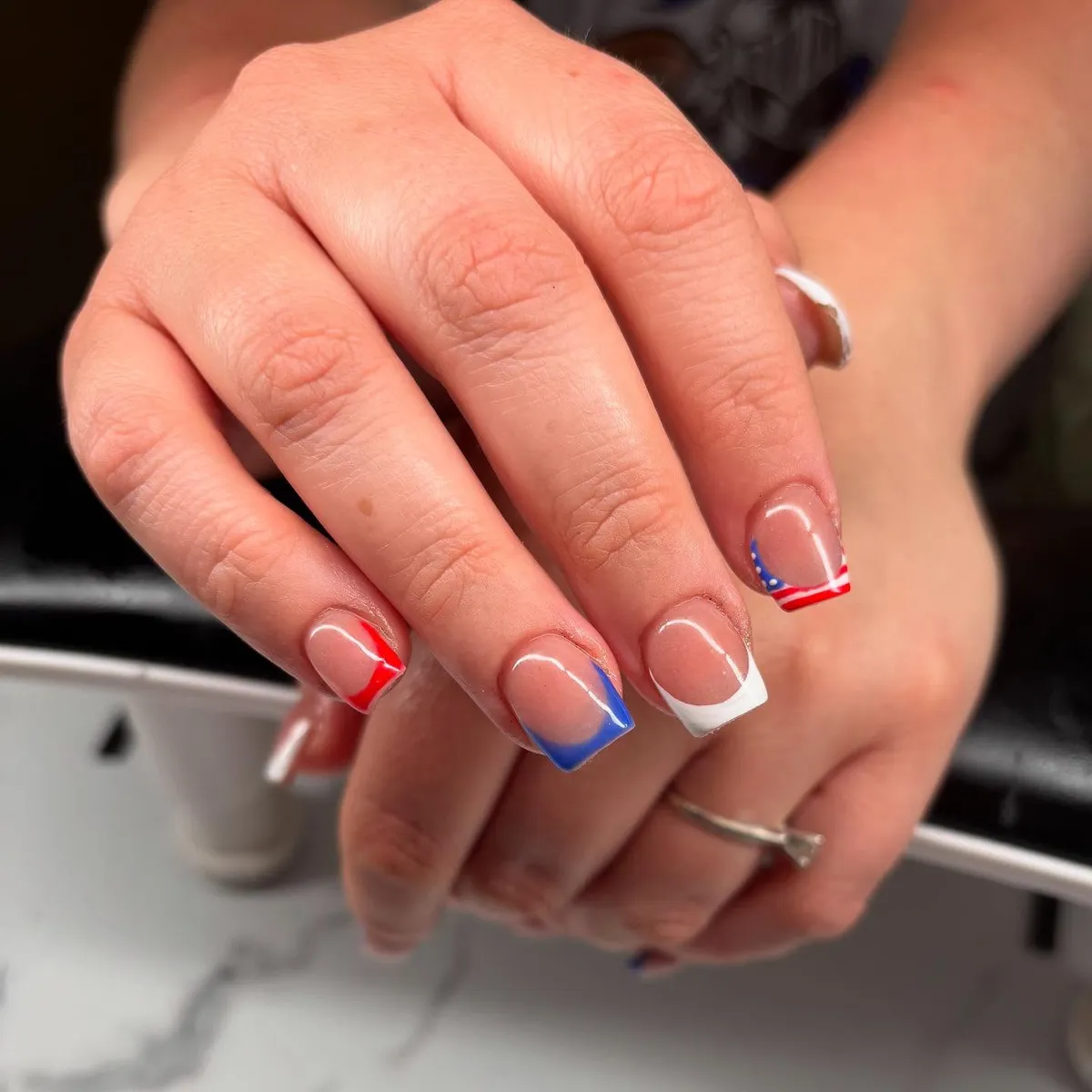 Short square French tips in red, blue, and white with dotted corner accent