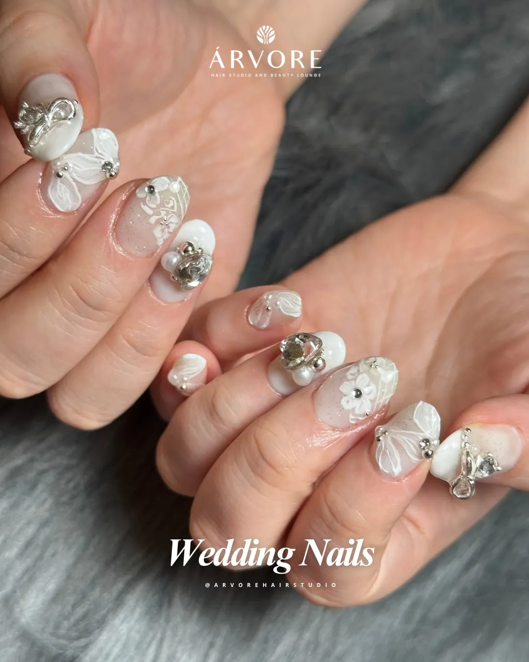 Milky white and nude nails with floral linework and prominent 3D silver-tone charms