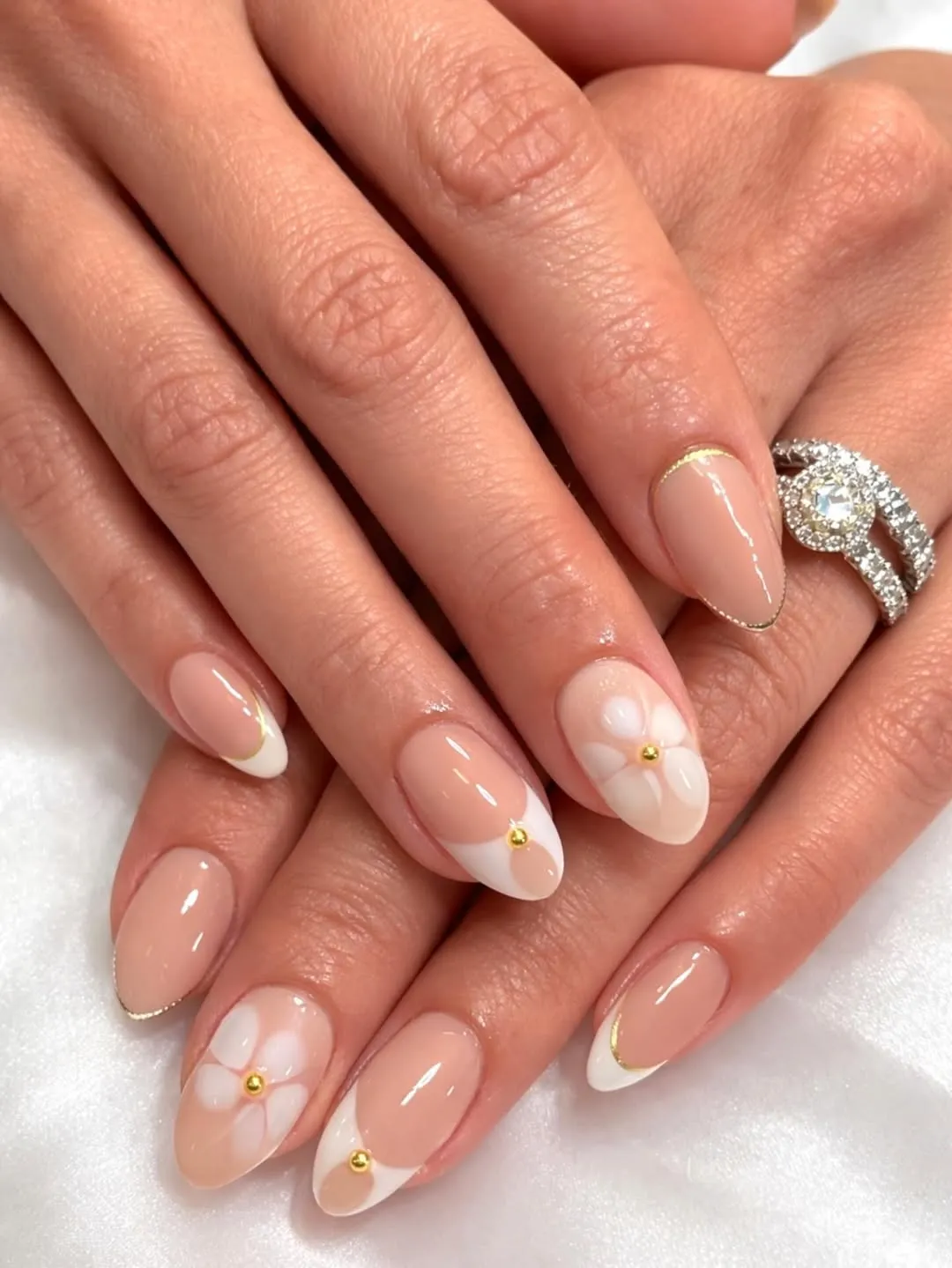 Nude French tips with thin gold outline and simple white flower accents