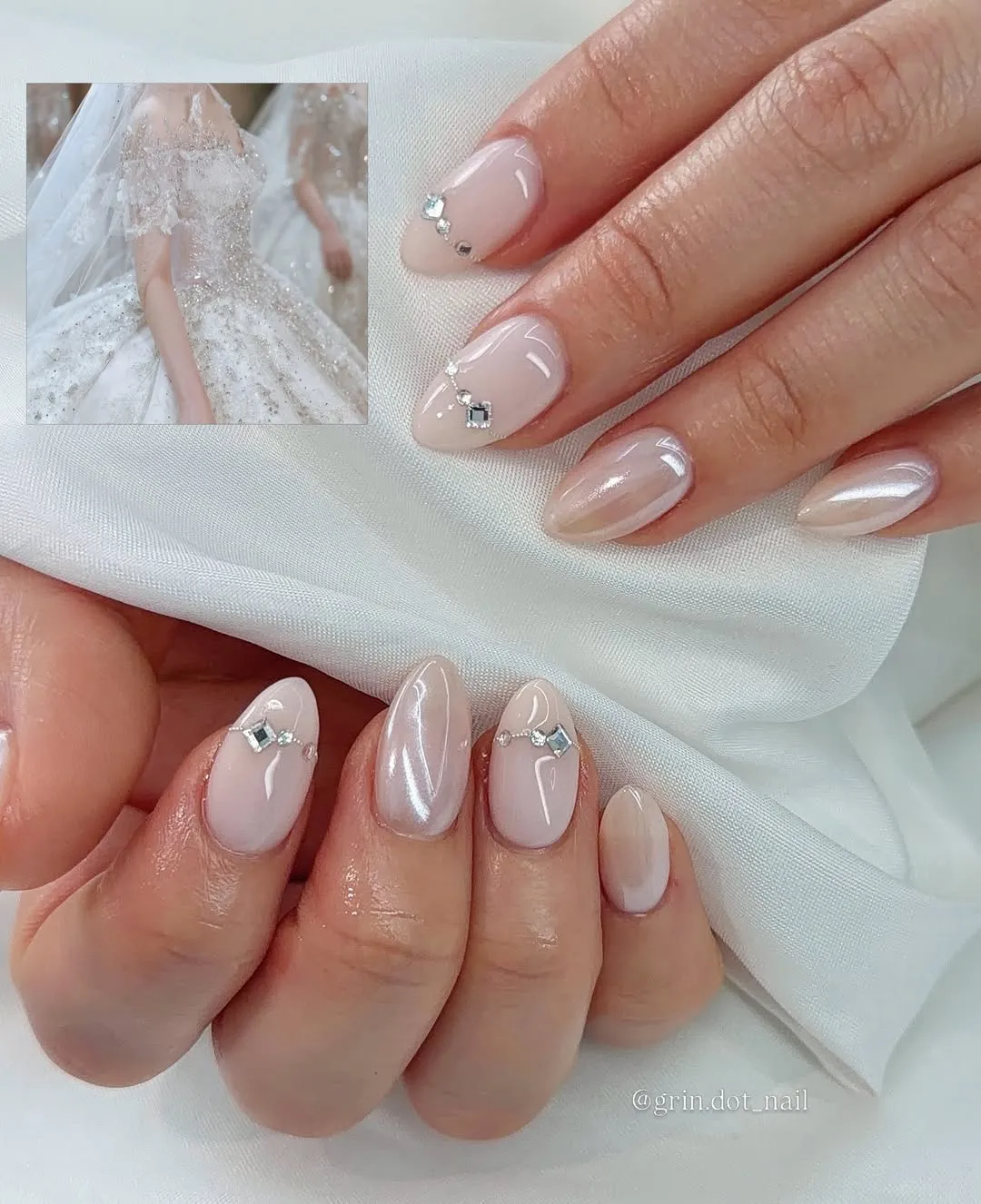 Glossy nude almond nails with small rhinestone clusters and pearly sheen accent