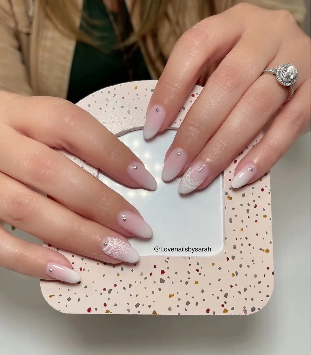 Glossy pink-to-white ombré nails with single rhinestones and lace-like white detailing