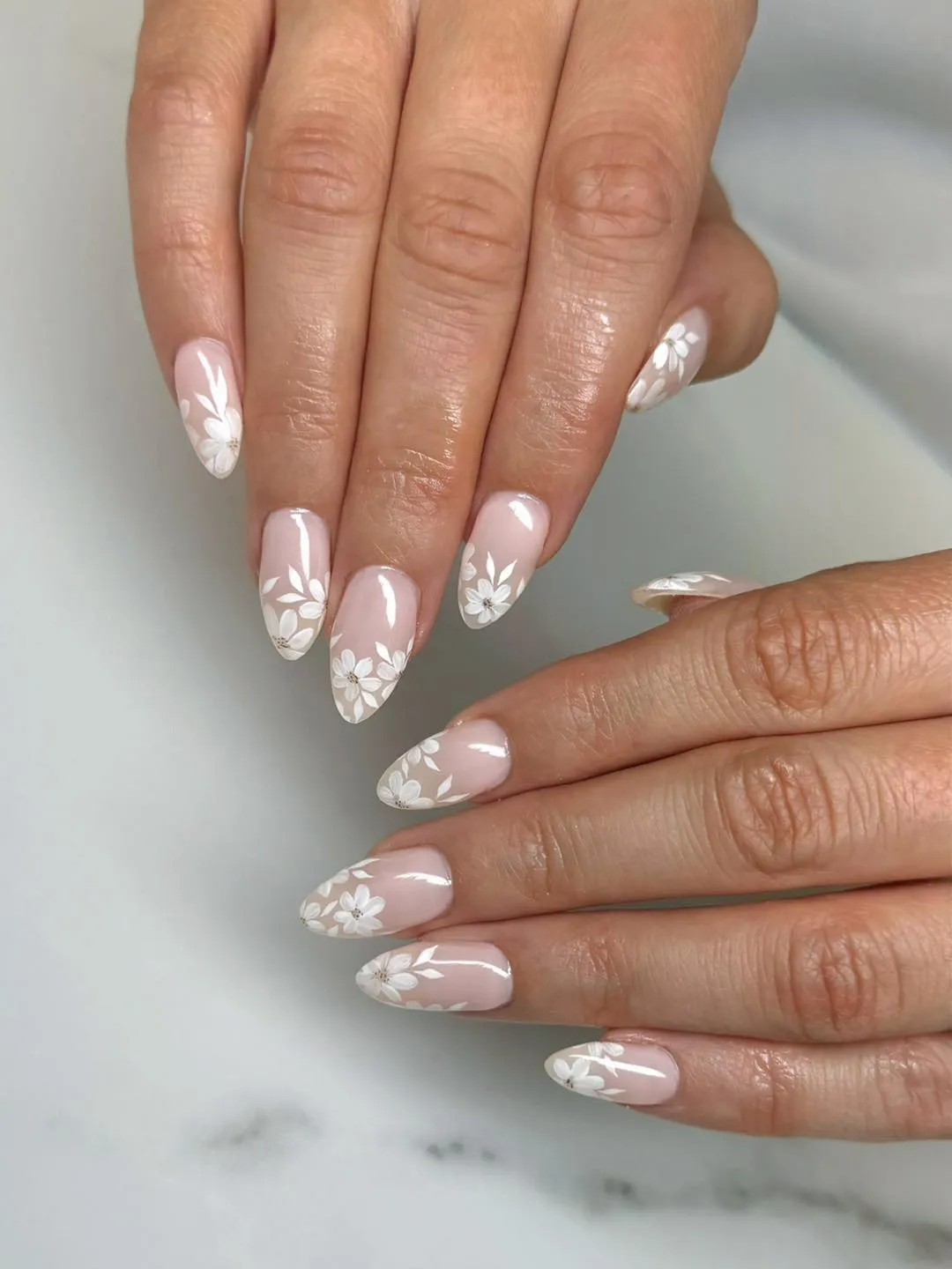 Pale pink almond nails with white floral tip designs