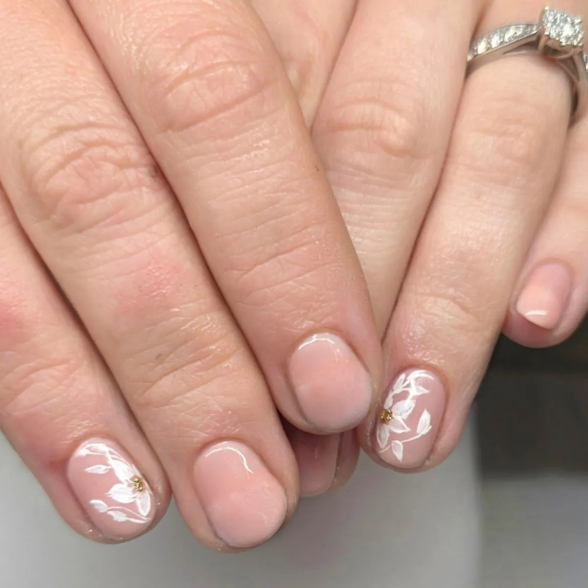 Short nude-pink nails with white floral accents