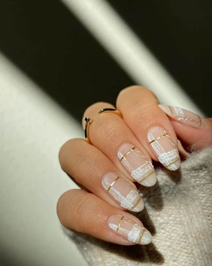 Sheer nude nails with white texture and gold striping