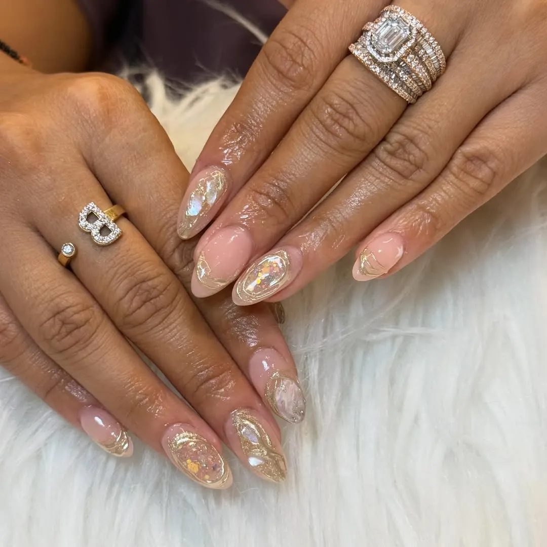 Sheer pink almond nails with gold outlines and iridescent inlays