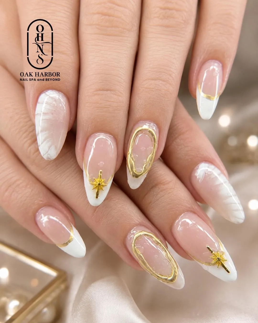 Pointed nude-and-white French tips with gold accents