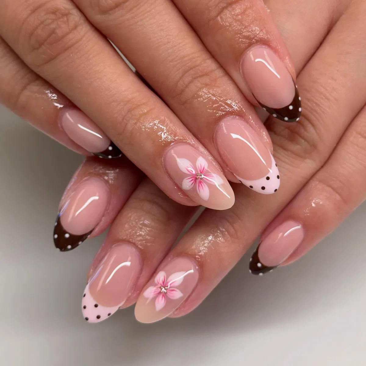 Nude pink base with mixed polka-dot French tips and floral accents