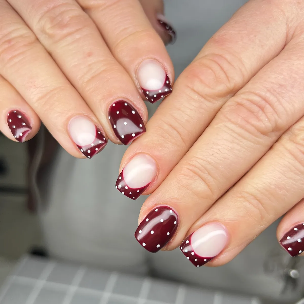 Short burgundy French tips with tiny polka dots