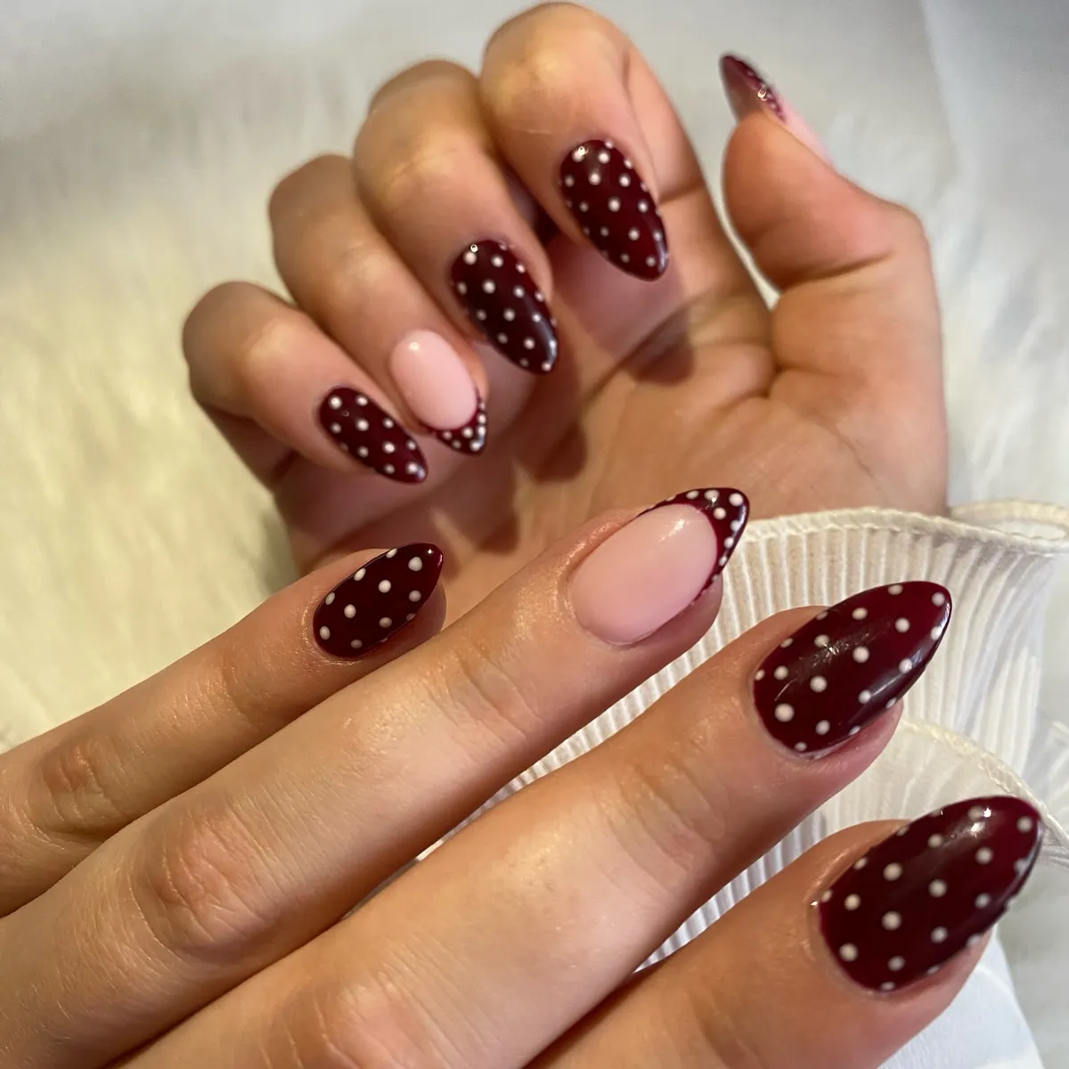 Deep burgundy polka dots with pale pink accent nails