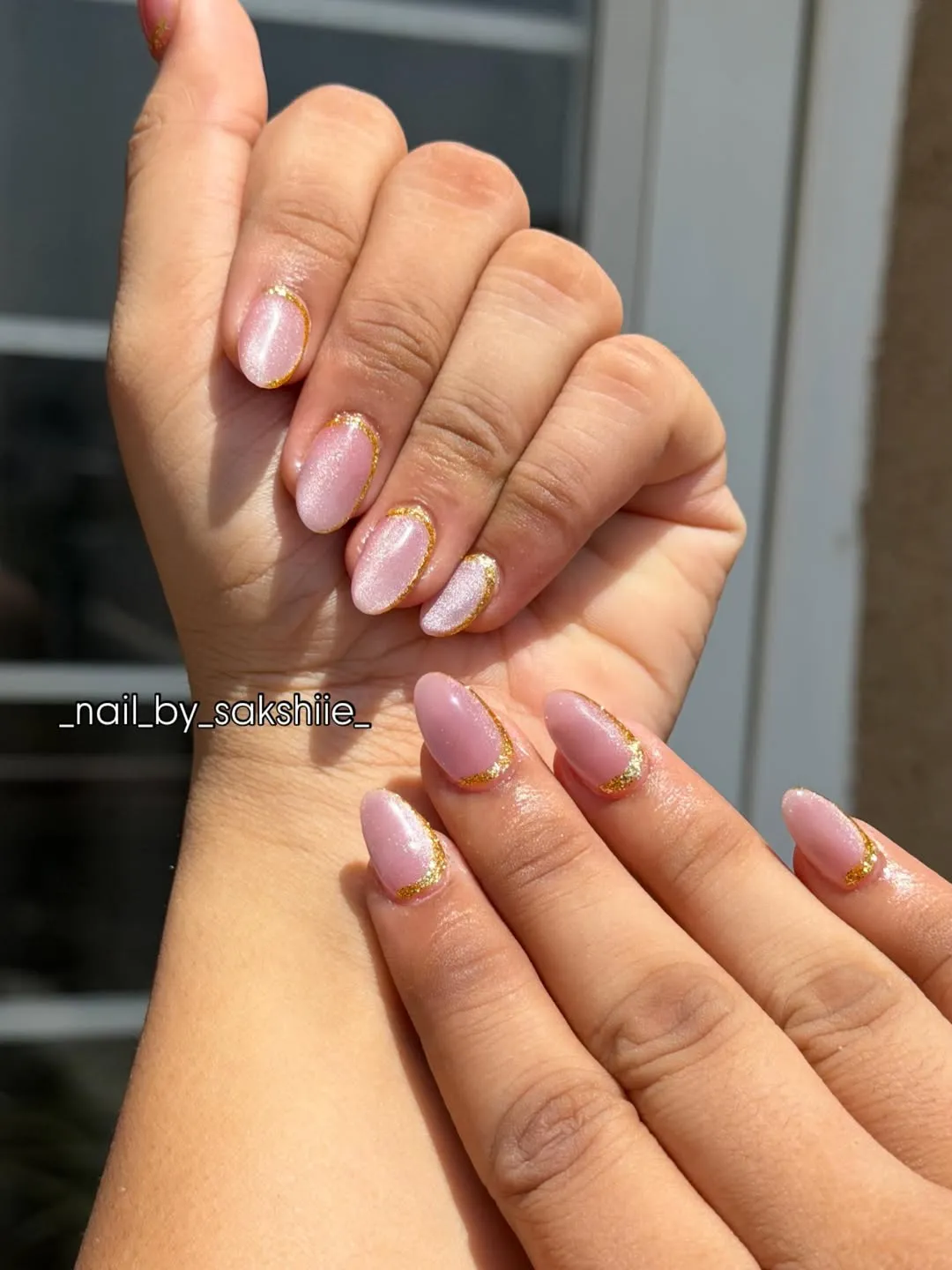 Short pearly pink nails with gold glitter outline