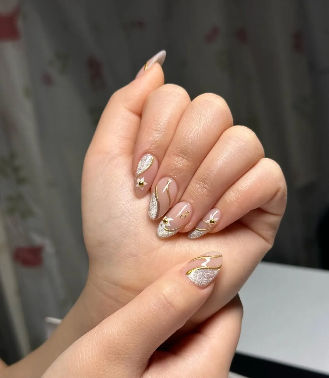 Nude almond nails with silver glitter and gold line accents