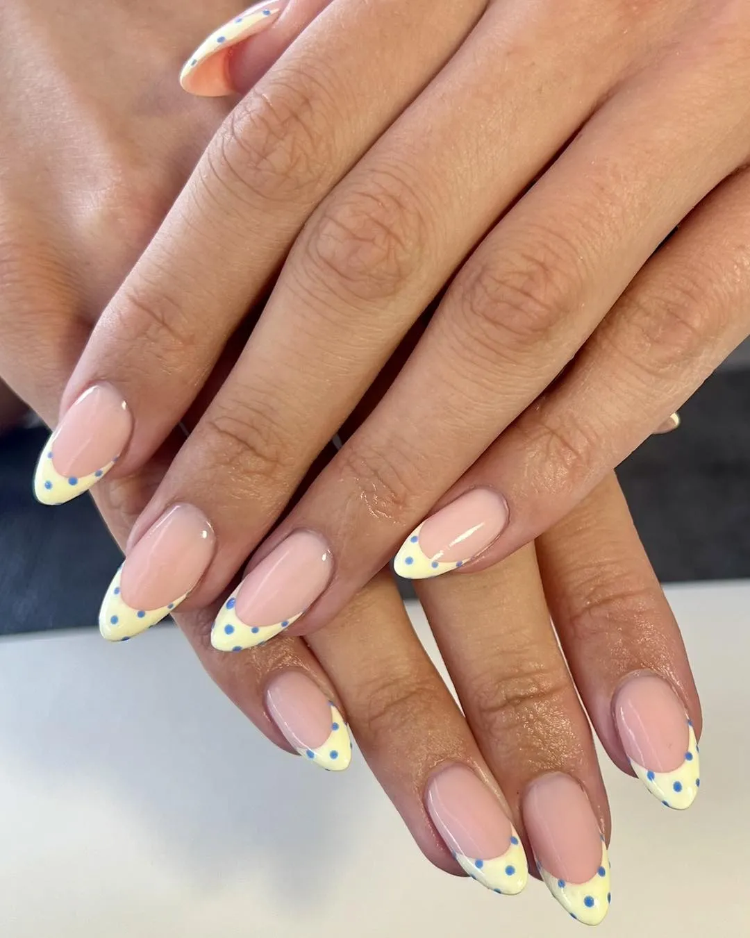 Pale yellow French tips with blue polka dots