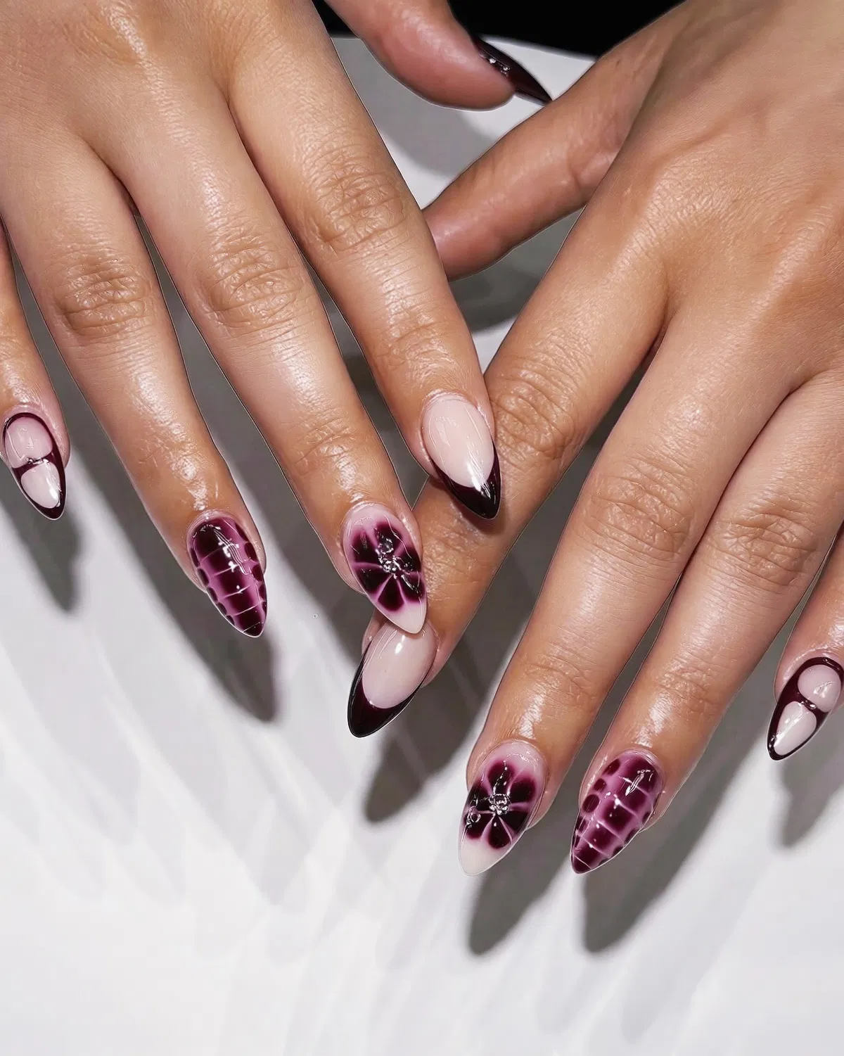 Pointed cherry French tips with floral and patterned accents