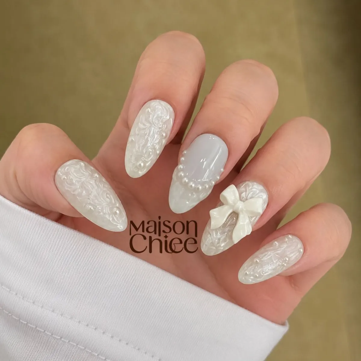 Milky white embossed nails with pearl arc and 3D bow