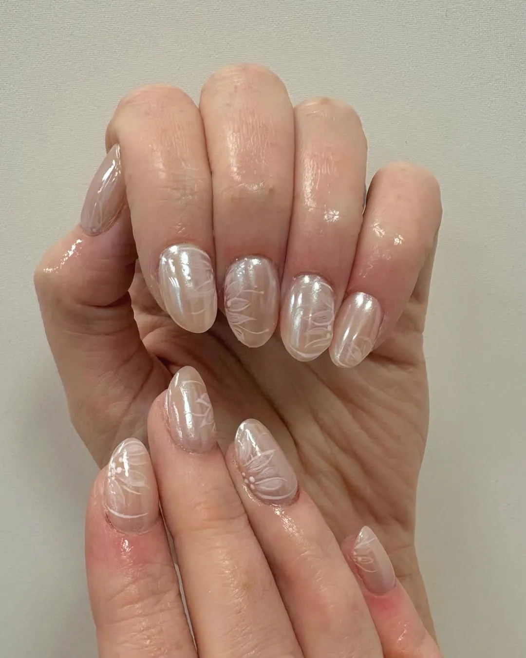 Iridescent pearl-white nails with delicate white leaf line art