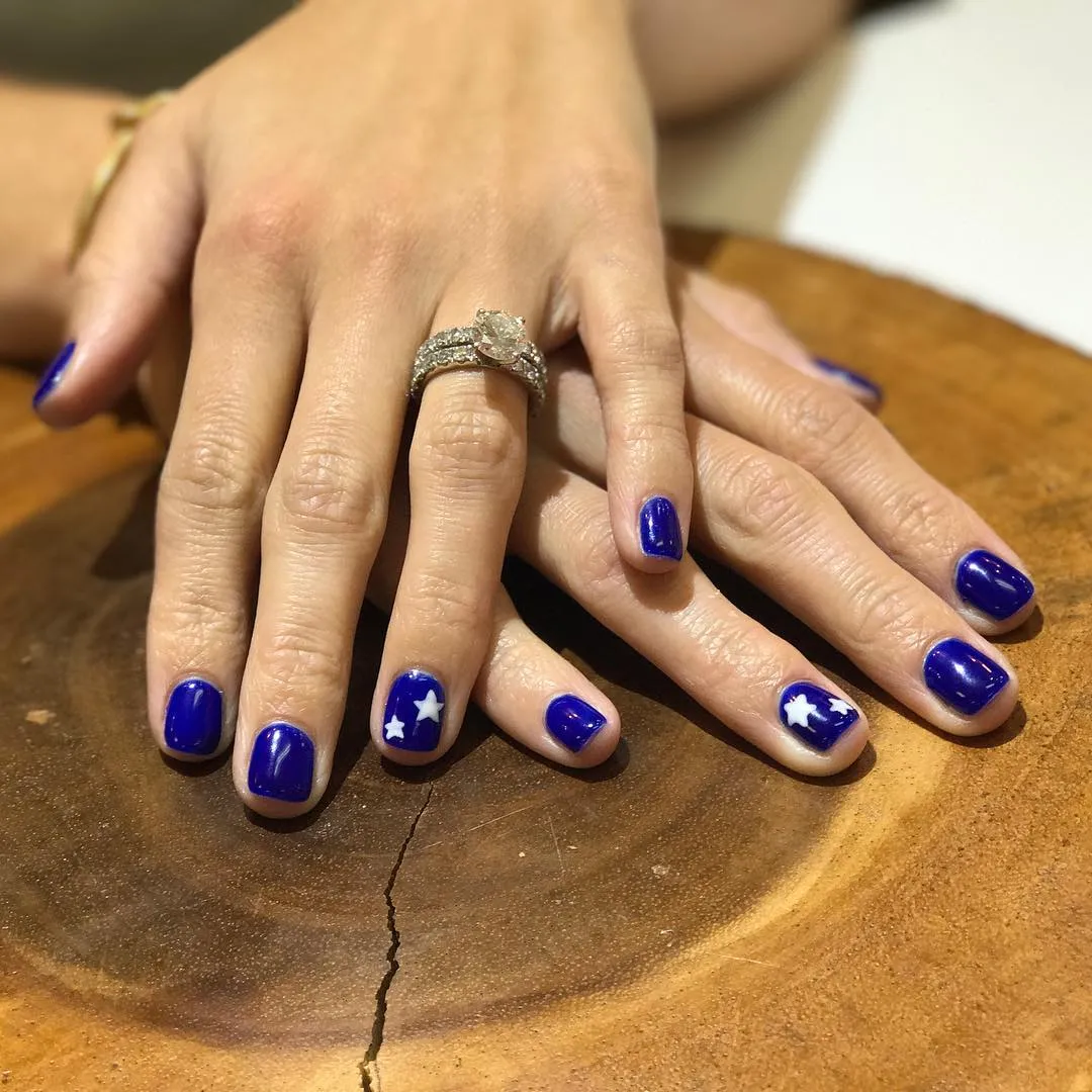 Deep blue manicure with simple white star accents
