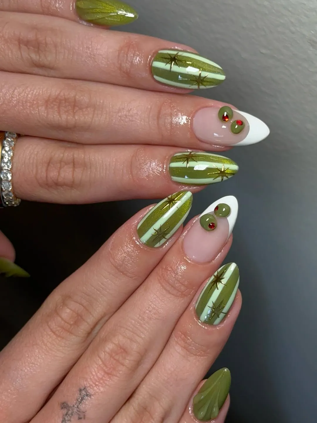 Striped green nails with gold starbursts and white-tipped accents