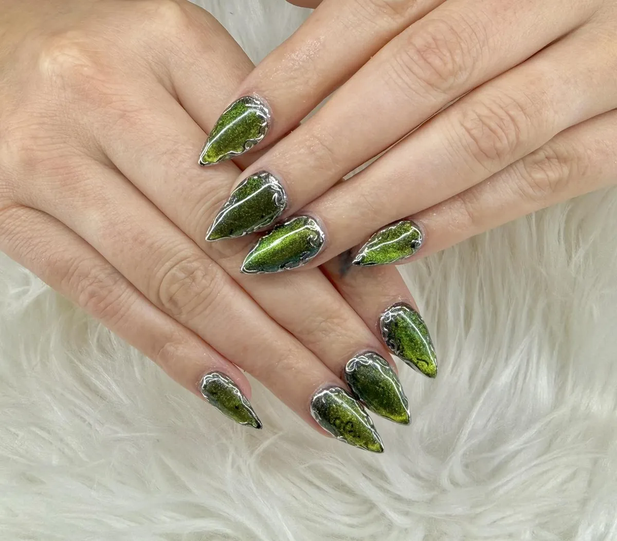 Long pointed green reflective nails with silver outlining